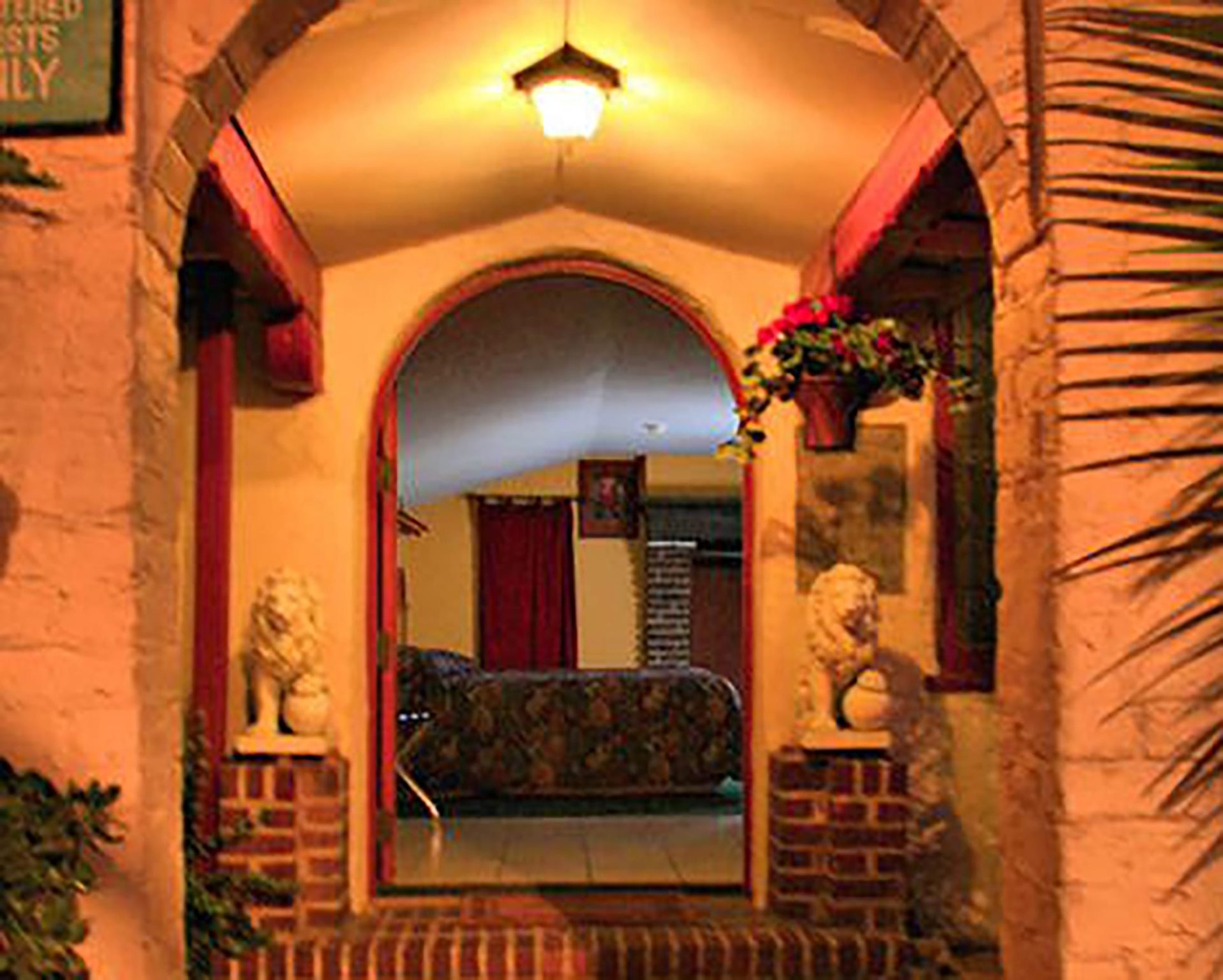 Welcoming arched entryway leading to cozy guest room at Santa Cruz Inn Riverside, framed by brick and flowers.