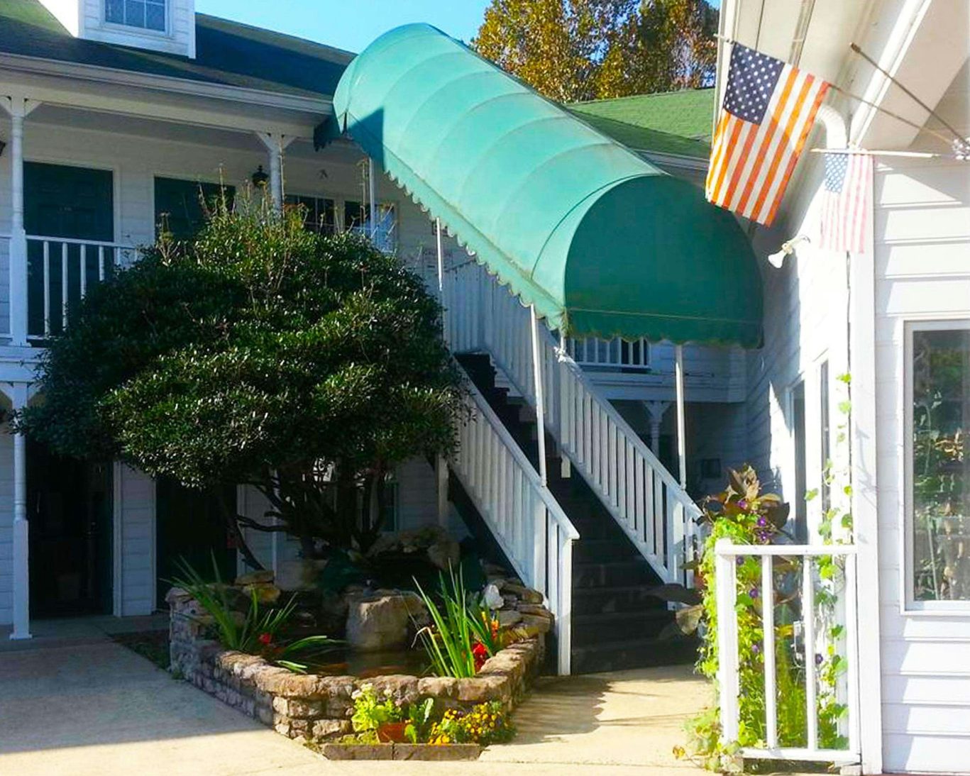 Outdoor staircase with green awning and landscaped garden at Stratford Motor Inn East Ellijay.