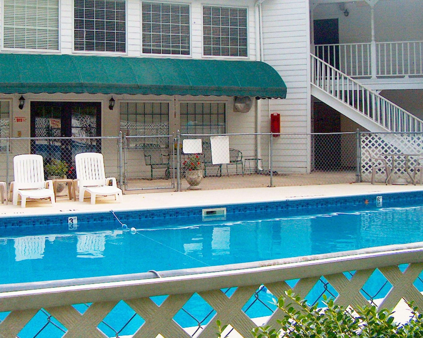 Fenced outdoor pool area with lounge chairs at Stratford Motor Inn East Ellijay.