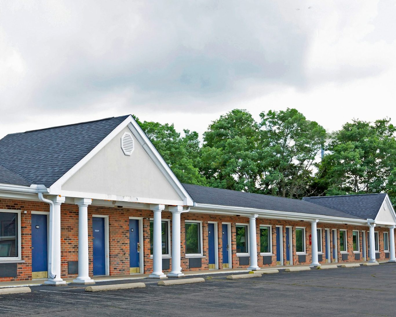 Single-story motel exterior with brick facade and white columns at Sunrise Inn Williamstown