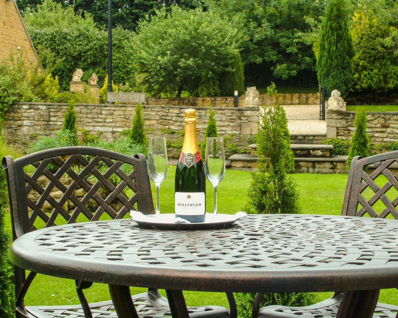 Romantic garden setting at The Hollies Hotel with Bollinger champagne and greenery.