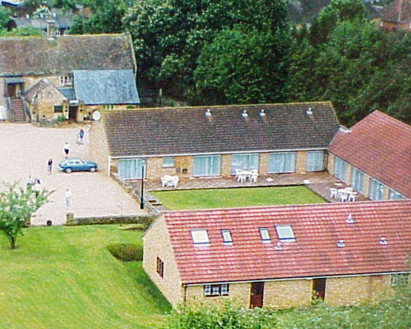 Aerial view of The Hollies Hotel courtyard and accommodations with lush green surroundings.