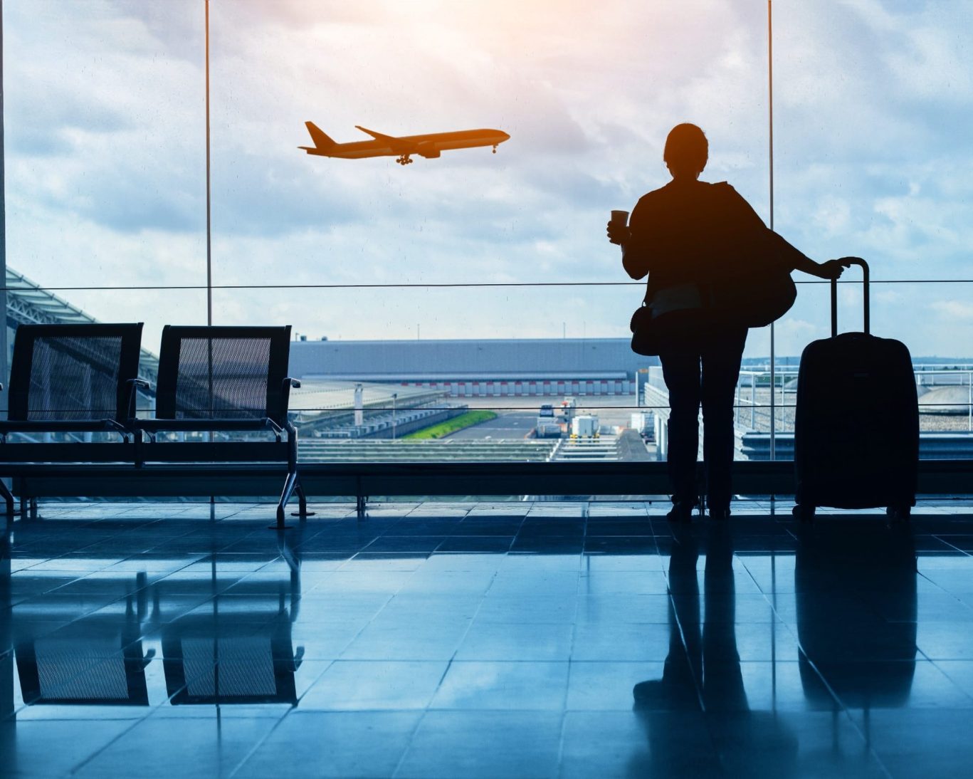 Traveler watching plane take off through the window at Norman Y. Mineta San Jose International Airport.