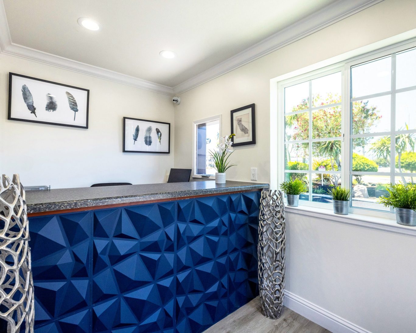 Bright hotel reception at Wafer 450 Hotel with blue geometric front desk and framed feather art.