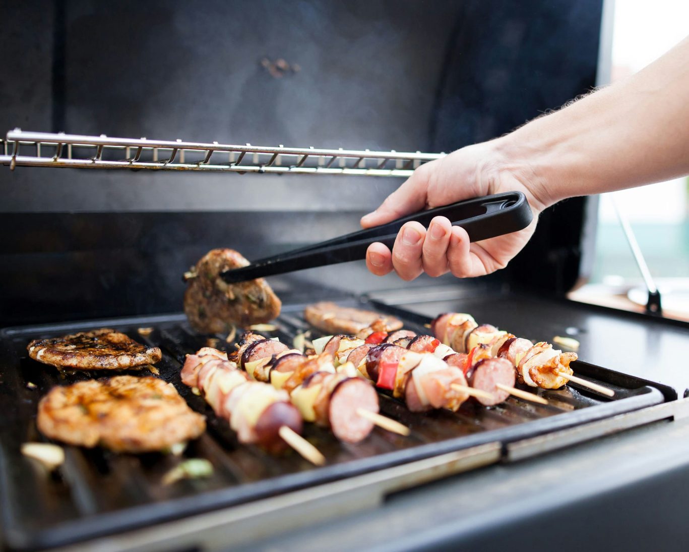 Close-up of barbecue grill with sizzling meats and skewers at Ticaboo Lodge outdoor area.
