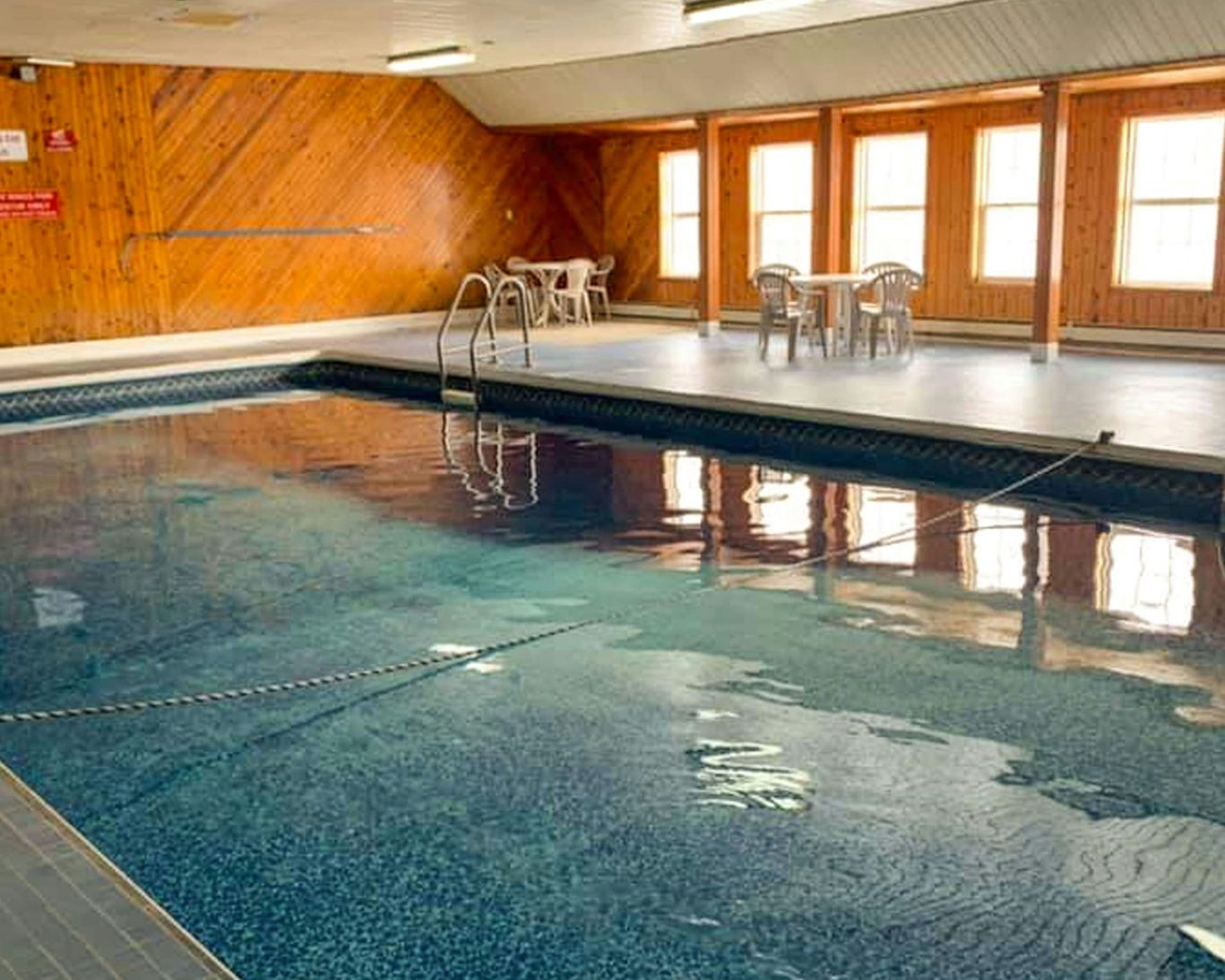 Indoor swimming pool with natural light and seating area at Travellers Inn Prince Edward Island.