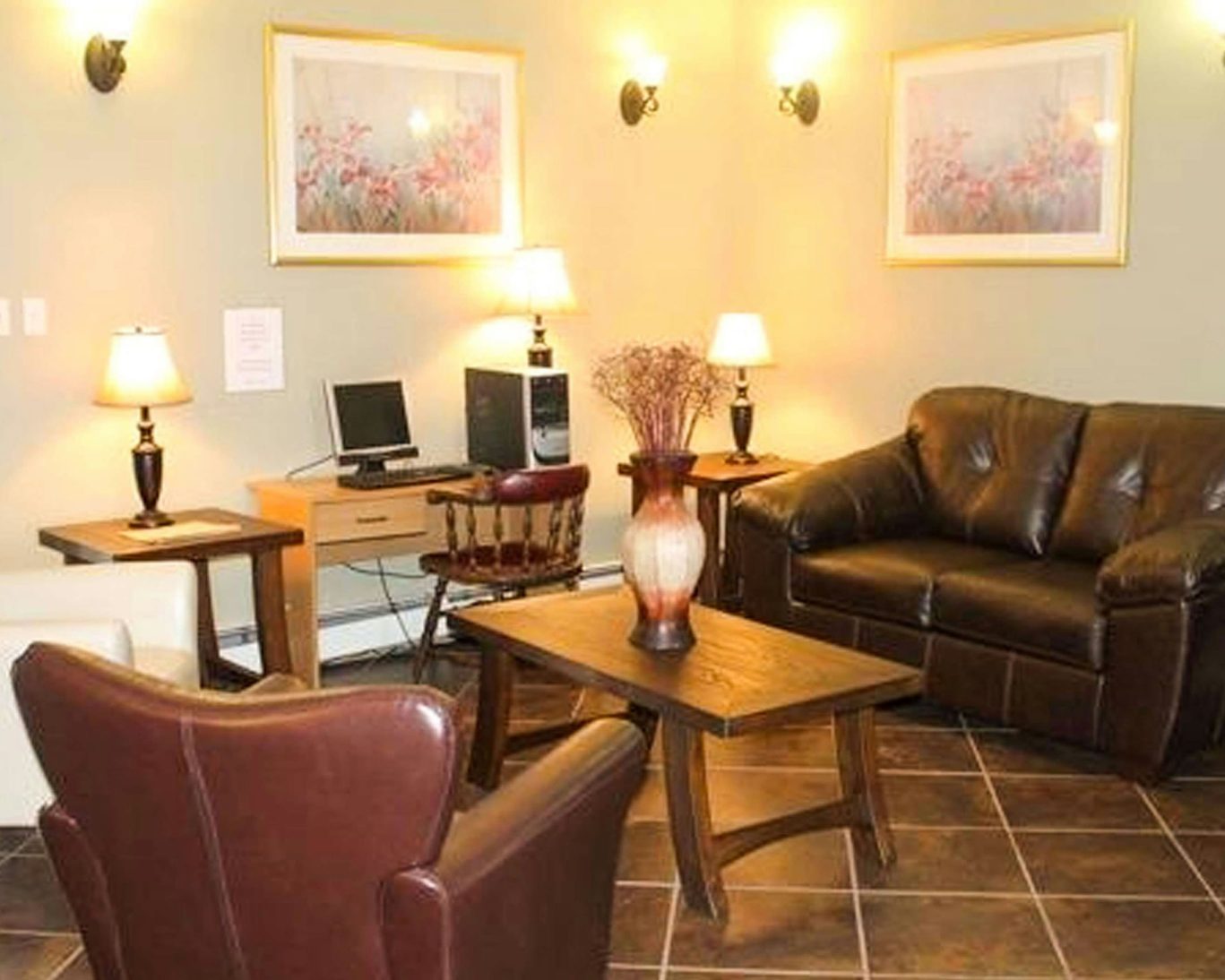 Guest lounge at Travellers Inn Prince Edward Island with leather sofas, business desk, and warm lighting.