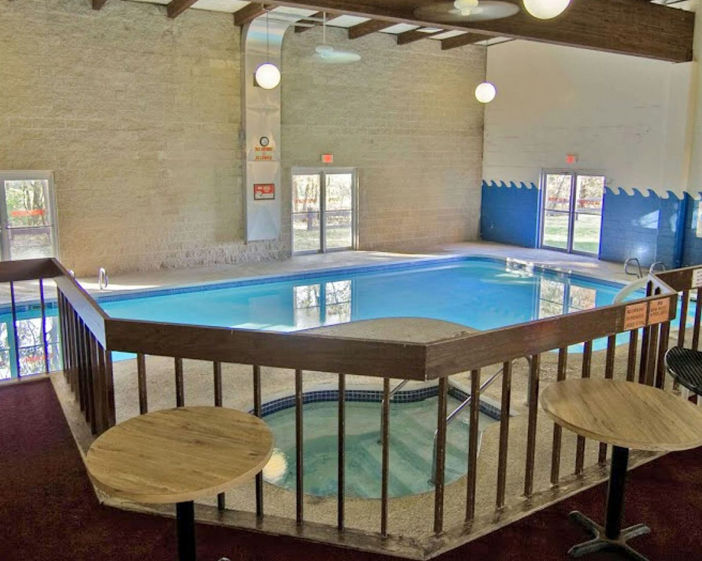 Indoor swimming pool and hot tub at Voyageur Inn with natural lighting and seating area.