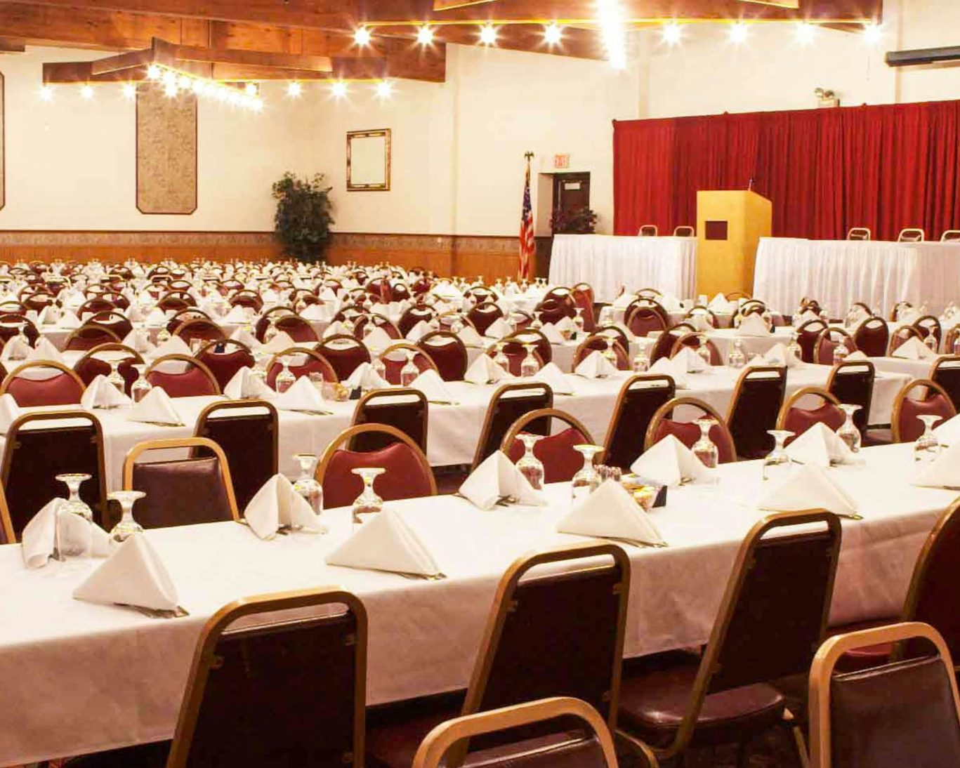 Banquet and conference room setup with white linens and stage at Voyageur Inn.