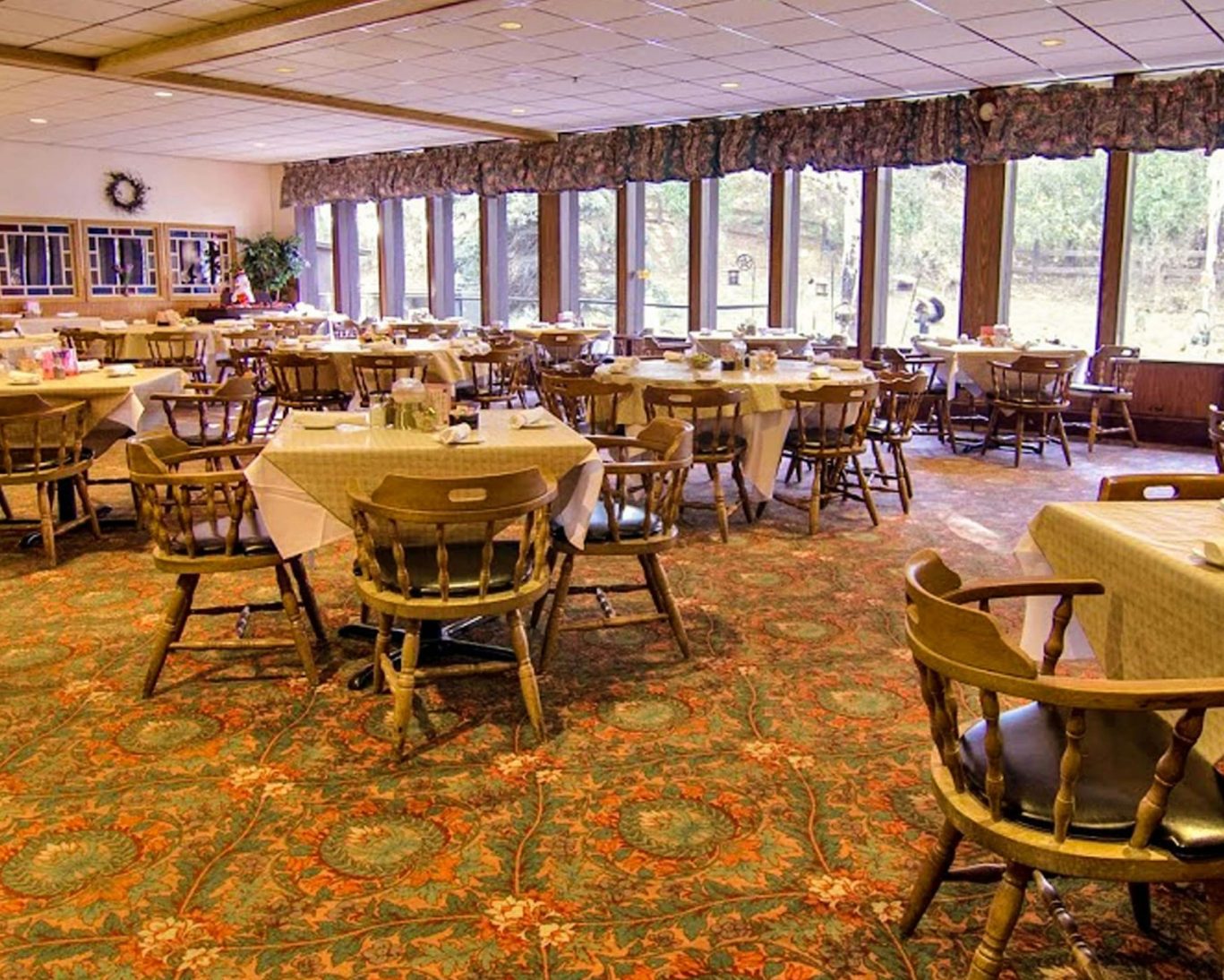 Bright dining area at Voyageur Inn with large windows and traditional wood furnishings.
