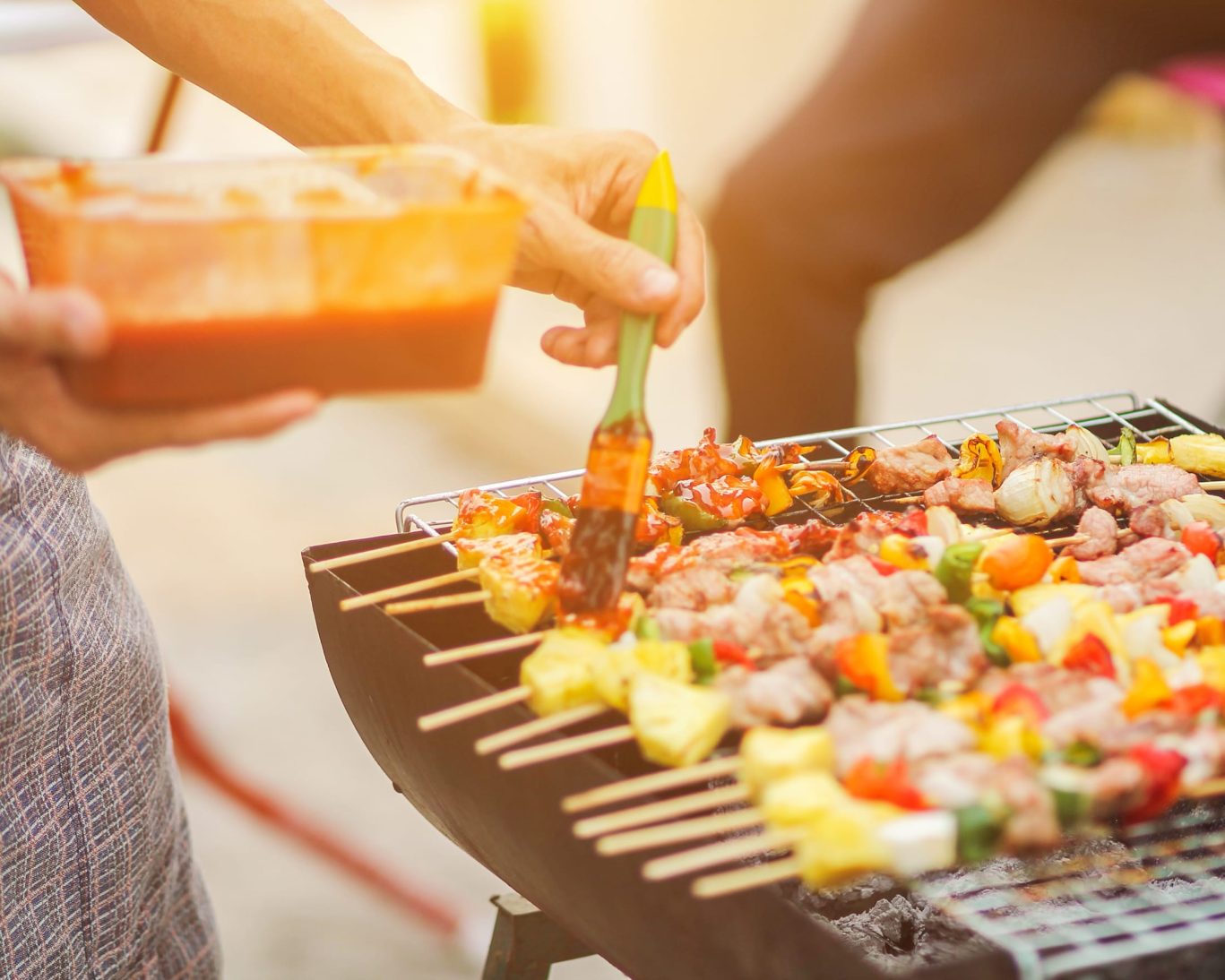 Grilling colorful meat and vegetable skewers over open flame at hotel BBQ area.