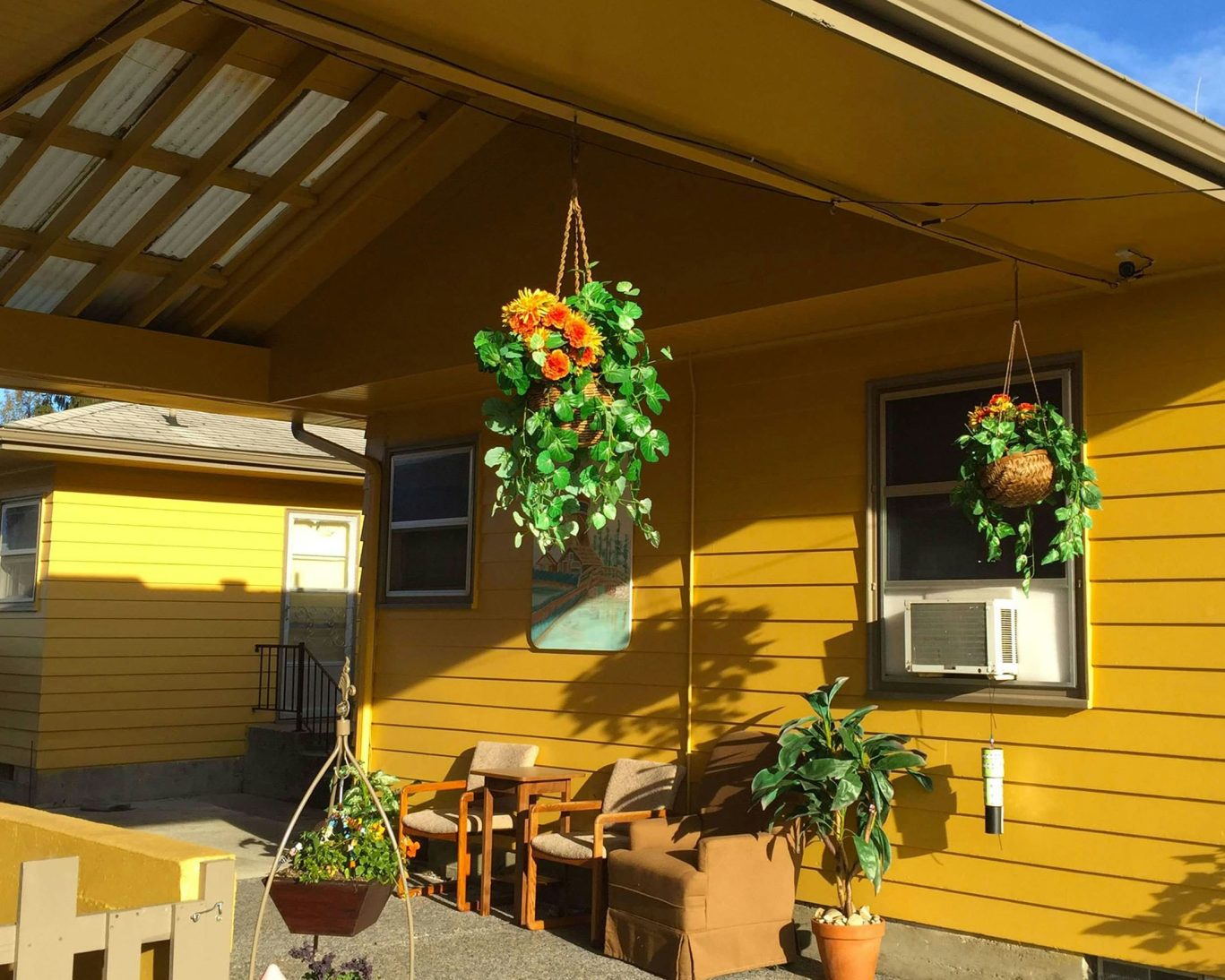 Charming outdoor sitting area at Windmill Inn with hanging flower baskets and patio chairs.