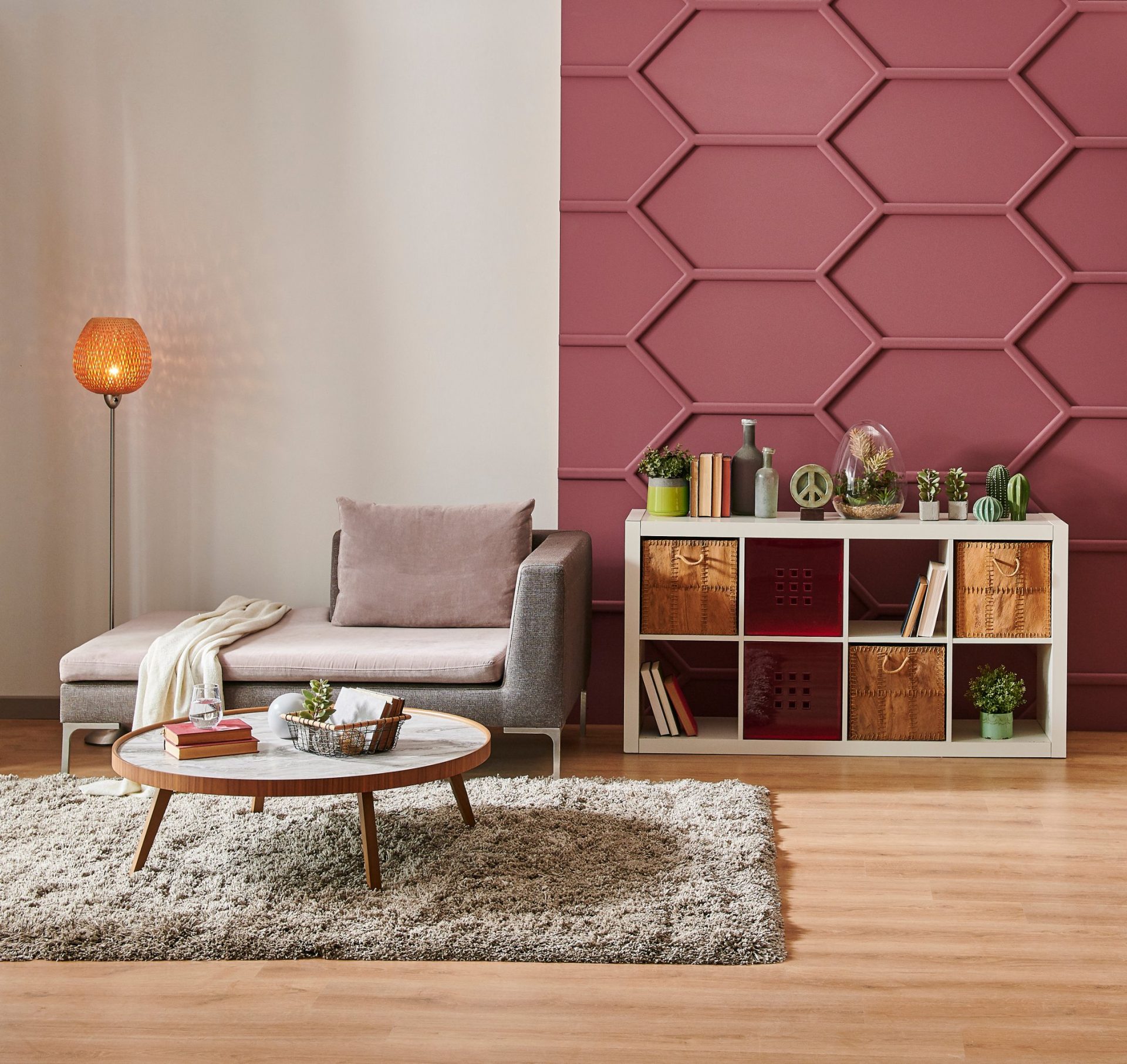 Modern cozy living room with geometric pink accent wall and stylish furniture.