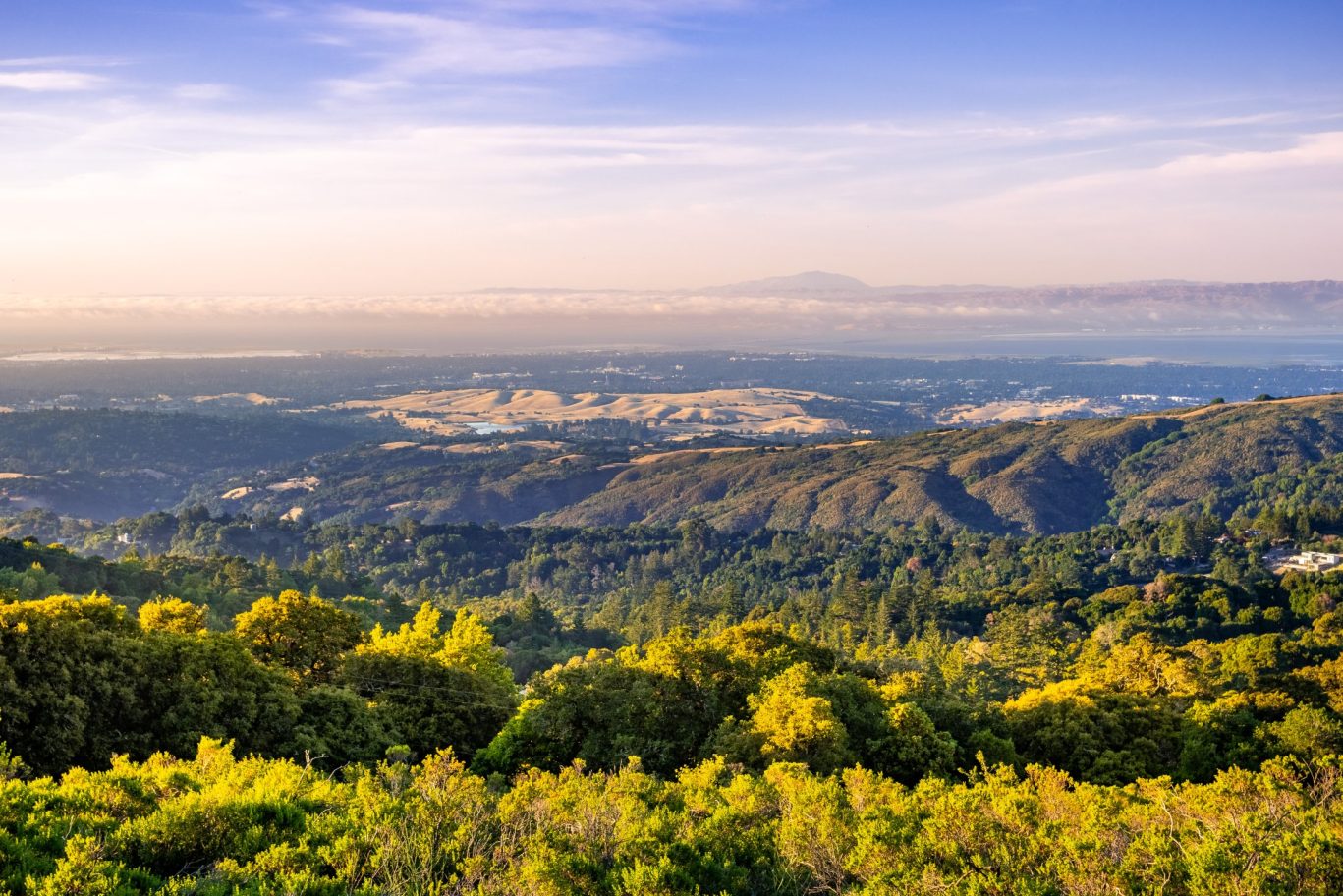 Sunset view over Silicon Valley from the Santa Cruz Mountains with rolling hills and distant cityscape.