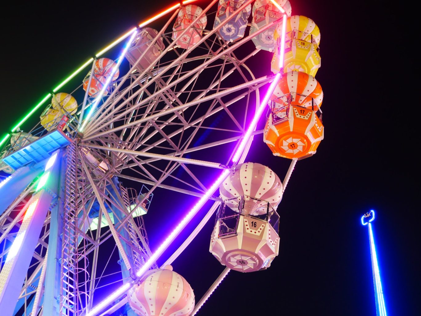 Colorful Ferris wheel lit up at night at a fairground or amusement park.