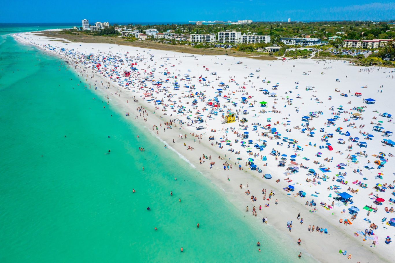 Crowded Siesta Key Beach with white sand and turquoise water in Florida.