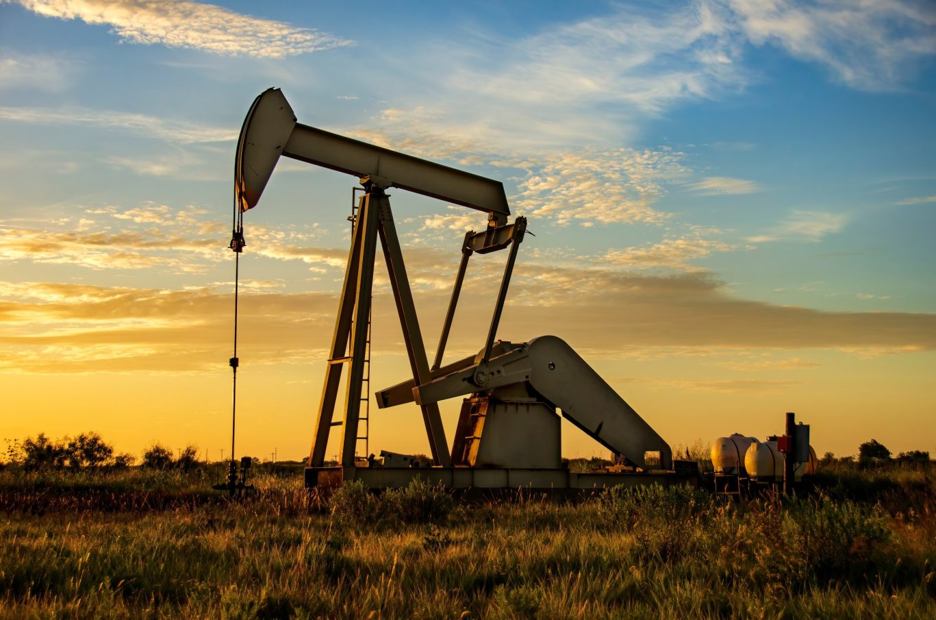 Silhouetted oil pumpjack at sunset in a Texas oil field.