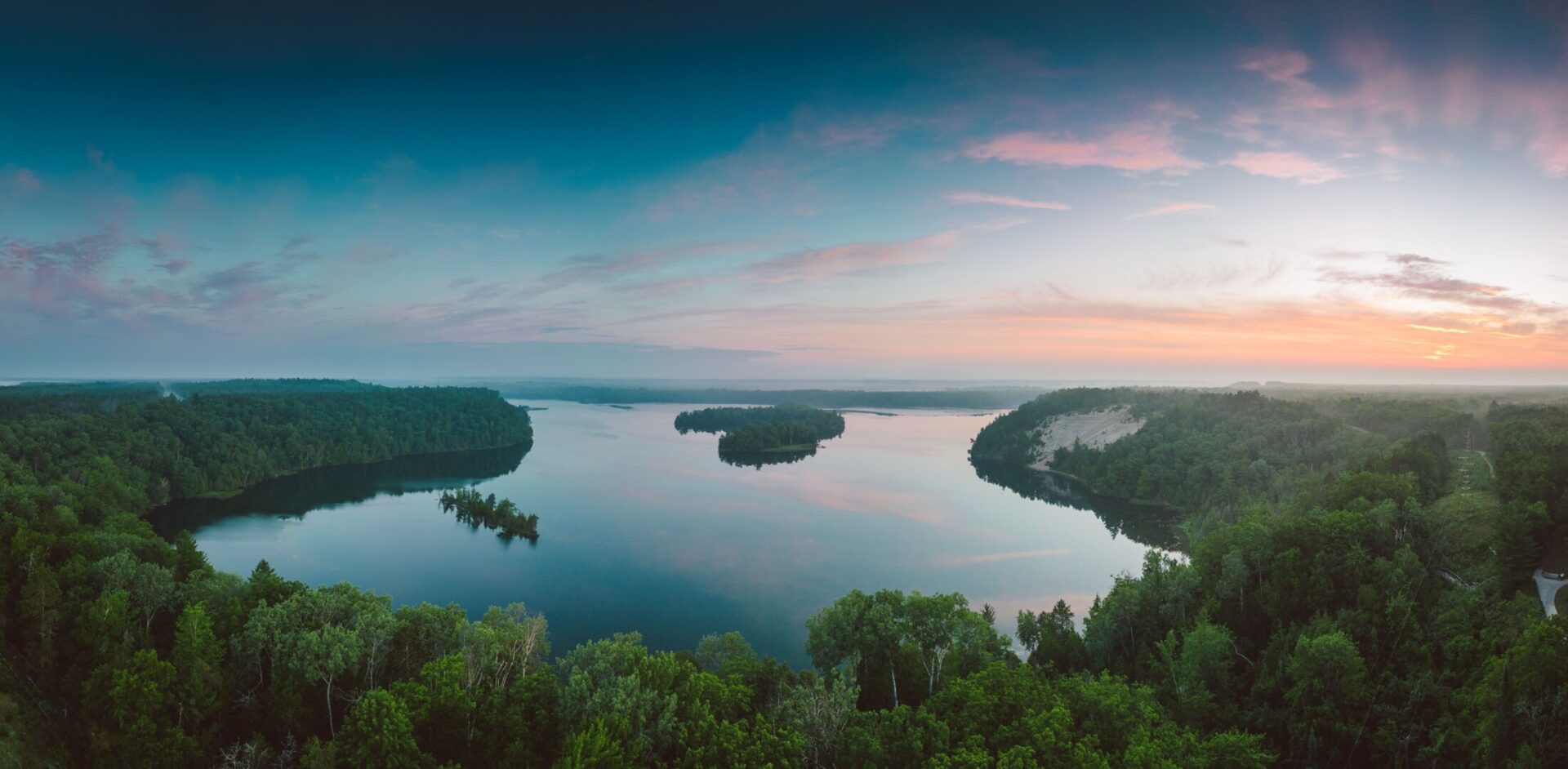 Panoramic aerial view of a forest-lined lake at sunset in Northern Michigan, USA.