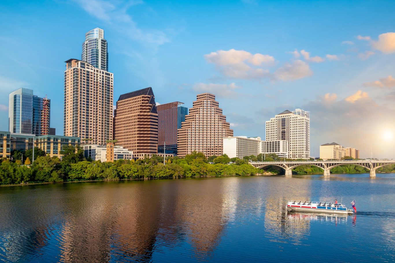 Downtown Austin Texas skyline at sunset with boat cruising on the Colorado River.